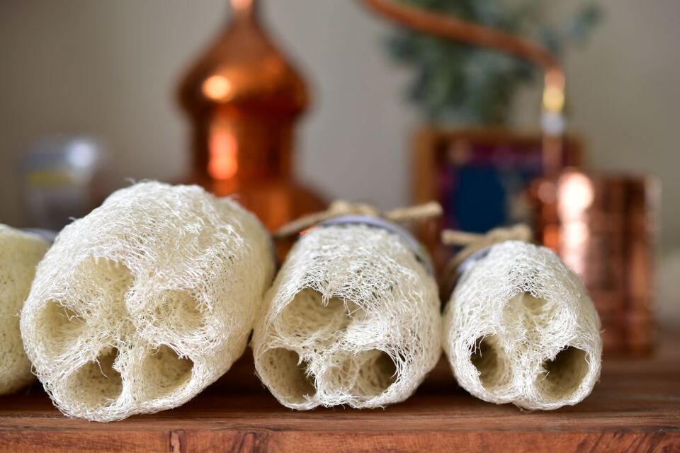 Three loofah sponge ends with a copper still in the backgroundgroungs