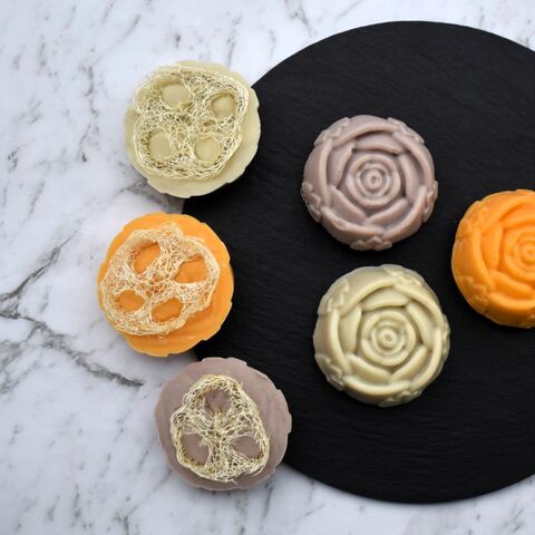 An array of natural loofah soap on a black slate and marble background